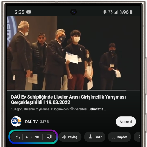 Screenshot of a YouTube video playing on a Samsung Galaxy S24 Ultra. The video features people standing on stage at an awards ceremony event and Deniz Demirdelen himself. The title of the video and channel information are displayed at the bottom of the screen. At the bottom is a 'Like' button highlighted in blue, purple, and cyan. This image shows the AI-powered screen reader helping to like or dislike a YouTube video.